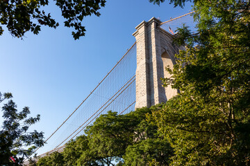 Iconic Brooklyn Bridge connecting New York City's urban landscape seen from below. There are a lot...