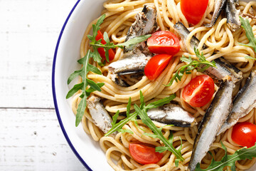 Whole grain pasta with sardines, tomato and arugula. Italian Sicilian cuisine, top view.