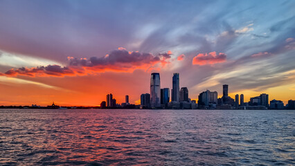Manhattan cityscape at sunset with iconic skyscrapers reflecting on the Hudson River. Great density...