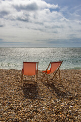 Deckchairs on the pebble beach in the sunshine, at Lyme Regis in Dorset