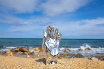 Fototapeta na wymiar mannequin hand on a beach with sky and sea in background