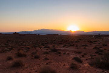 Sunrise over barren hills seen from Valley of Fire State Park in Mojave desert near Overton, Nevada, USA. Red rocks and stone desert. First sunlight with early morning atmosphere in remote habitat
