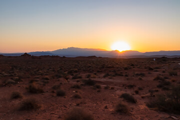Fototapeta premium Sunrise over barren hills seen from Valley of Fire State Park in Mojave desert near Overton, Nevada, USA. Red rocks and stone desert. First sunlight with early morning atmosphere in remote habitat