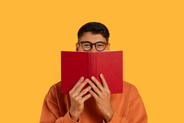 Man Holding Red Book Over Face On Yellow Background