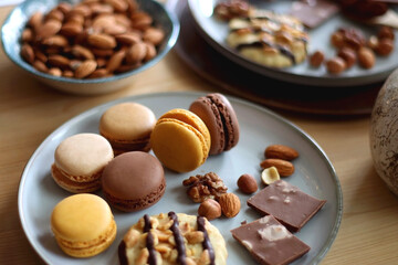 Cup of tea or coffee, cookies, macaroons, chocolate, various nuts and cocoa powder on wooden table. Selective focus.