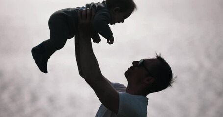A man lifting his son near the sea, slow motion 4k at 120 fps