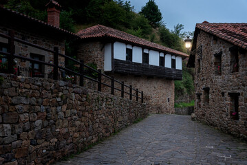 Enchanting Stone Village, Saja-Besaya Natural Park, Barcena Mayor, Cantabria, Spain. View of the perfectly cobbled alleys and houses adorned with wooden balconies overflowing with flowers at sunrise.