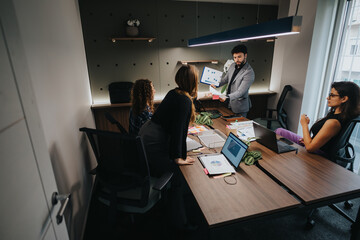 Four colleagues in a business meeting in a modern office setting discuss project details while...