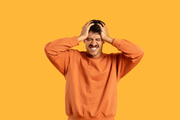 Man in Orange Shirt Holding Head In Despair