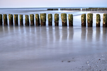 A series of wooden breakwaters and a pier on a sandy beach on the island of Wolin