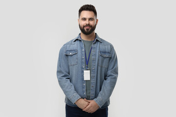 Handsome young man with blank badge on grey background