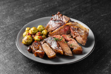 Delicious fried beef meat, vegetables and thyme on black table, closeup