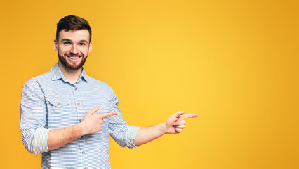 Optimistic man with beard pointing away at free space