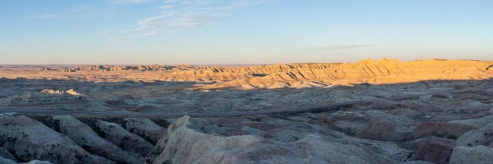Panoramic Views of the golden rays of sun touching the cliffs and canyons of South Dakota's Badlands National Park in spring at sunrise. 