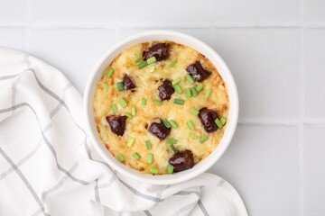 Tasty sausage casserole with green onions in baking dish on white tiled table, top view