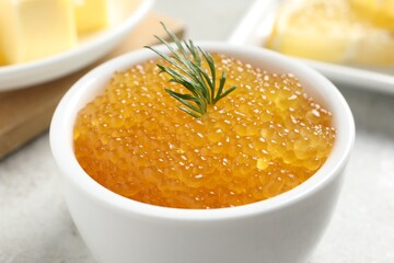 Fresh pike caviar and dill in bowl on light grey table, closeup