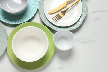 Beautiful ceramic dishware and cutlery on white marble table, flat lay. Space for text
