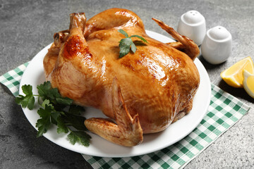 Tasty roasted chicken with parsley and lemon on grey textured table