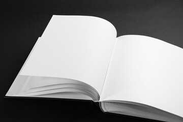 One open photo album on black background, closeup. Space for text