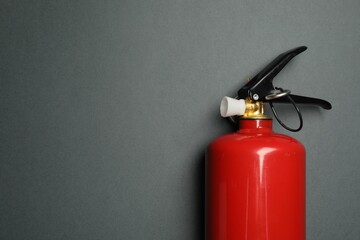 One red fire extinguisher on gray background, top view. Space for text