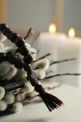 Rosary beads and willow branches on table, closeup