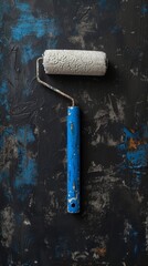 Paint roller with blue and white paint on a textured black background