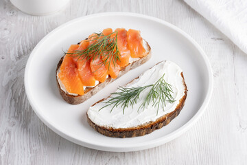 Rye sandwich with salmon and cream cheese on white wooden table