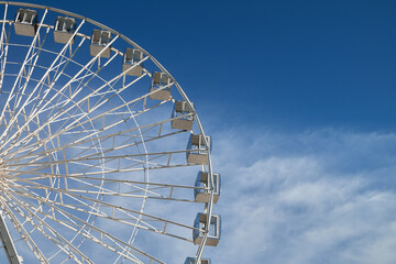 A majestic Ferris wheel stands tall against a cloudy blue sky. Amusement Park. - obrazy, fototapety, plakaty