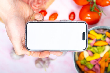 A smartphone mockup placed over a table with delicious food like macarons and tomatoes, showcasing...