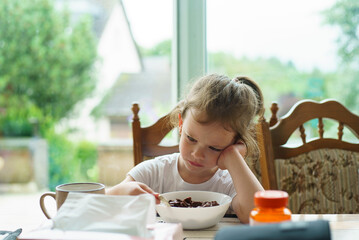 Little girl having breakfast at home. Selective focus on the child