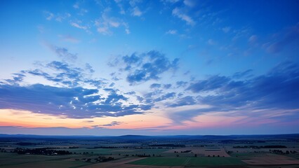 Generate a high-resolution image of a beautiful landscape with a blue sky, white clouds, and green fields. Make the image look realistic and detailed.