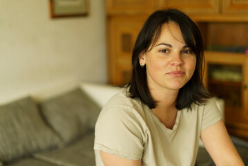 Obraz premium Portrait of a young woman sitting on the sofa at home.
