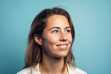 A woman with long brown hair and blue eyes is smiling at the camera