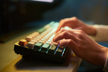 Professional online gamer hand fingers mechanical keyboard in neon color blur background.