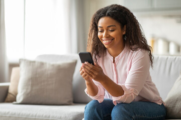 Young Black Woman Checking Messages on Phone at Home