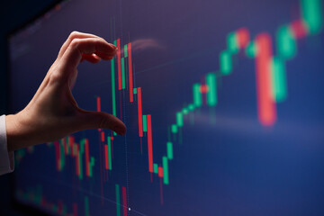 Finger to the graph on the monitor. Team of stockbrokers are having a conversation in a office with multiple display screens.