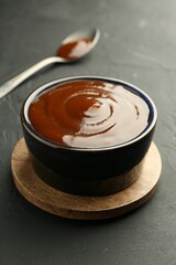 Tasty barbeque sauce in bowl on dark table, closeup