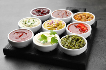 Different tasty sauces in bowls on grey table, closeup