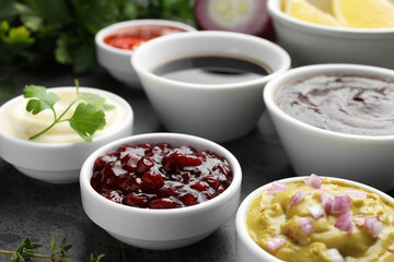 Different tasty sauces in bowls on grey table, closeup