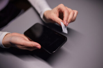 Hand female cleaning her smartphone with microfiber cloth