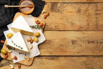 Tasty Camembert cheese with thyme, honey and nuts on wooden table, flat lay. Space for text