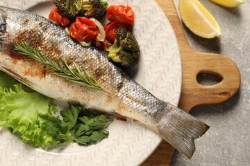 Delicious baked fish and vegetables on light grey table, top view
