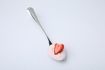 Delicious natural yogurt with fresh strawberry in spoon on light background