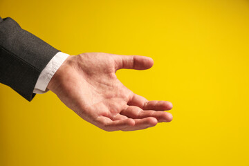 Fototapeta premium Man holding something in hand on yellow background, closeup