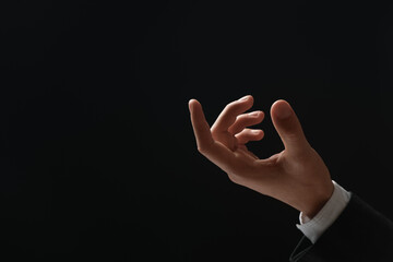 Man holding something in hand on black background, closeup. Space for text