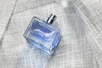 Luxury men's perfume in bottle on grey jacket, above view. Space for text