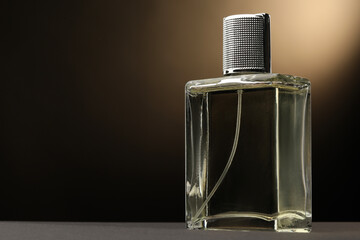 Luxury men`s perfume in bottle on grey table against brown background, space for text