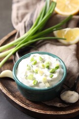 Delicious yogurt in bowl, green onion and spoon on table