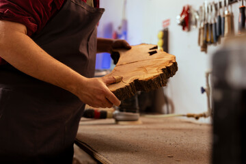 Carpenter holding timber block, doing quality assurance on it before starting furniture assembling...