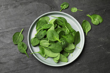 Fresh spinach leaves on dark textured table, flat lay